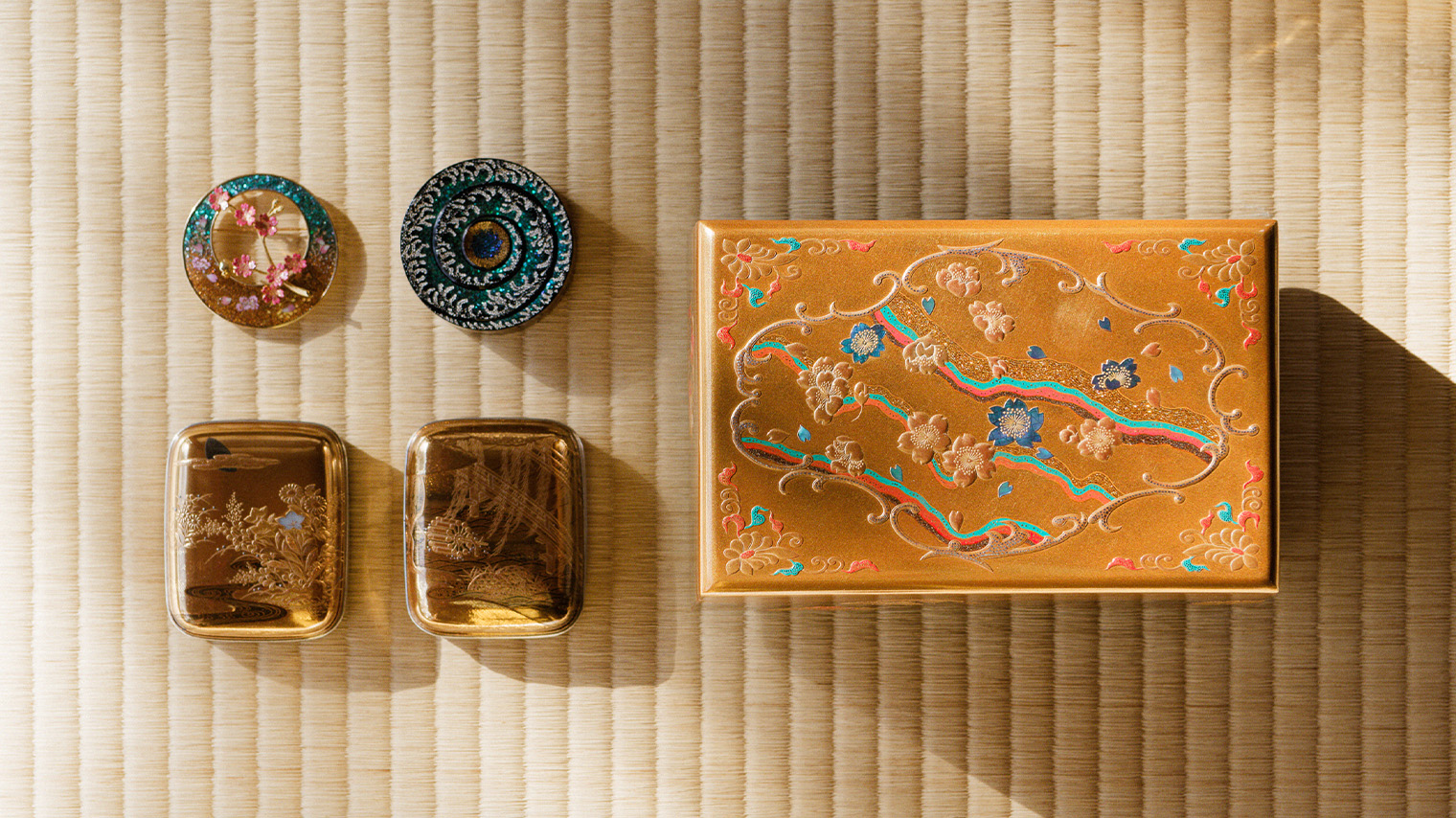 Foto Una selección de piezas maki-e de Isshu Tamura. De arriba a la izquierda: broche con motivos florales, porta incienso maki-e con espiral dorada, caja del tesoro maki-e (pequeña)